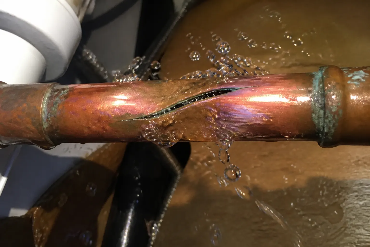 Burst copper pipe spraying water under a Tampa bathroom sink