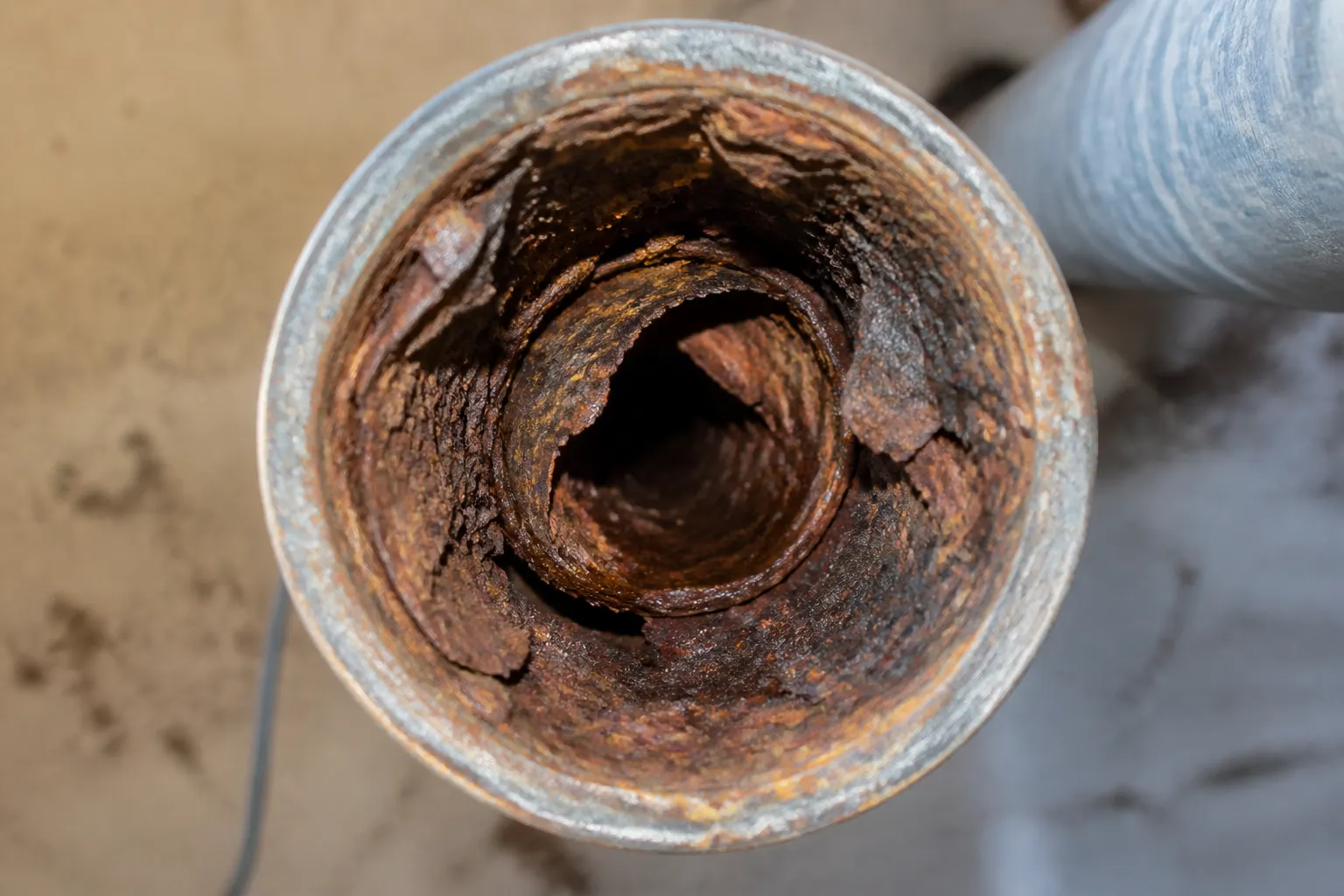 Corroded galvanized water pipe cut open, rust narrowing the interior